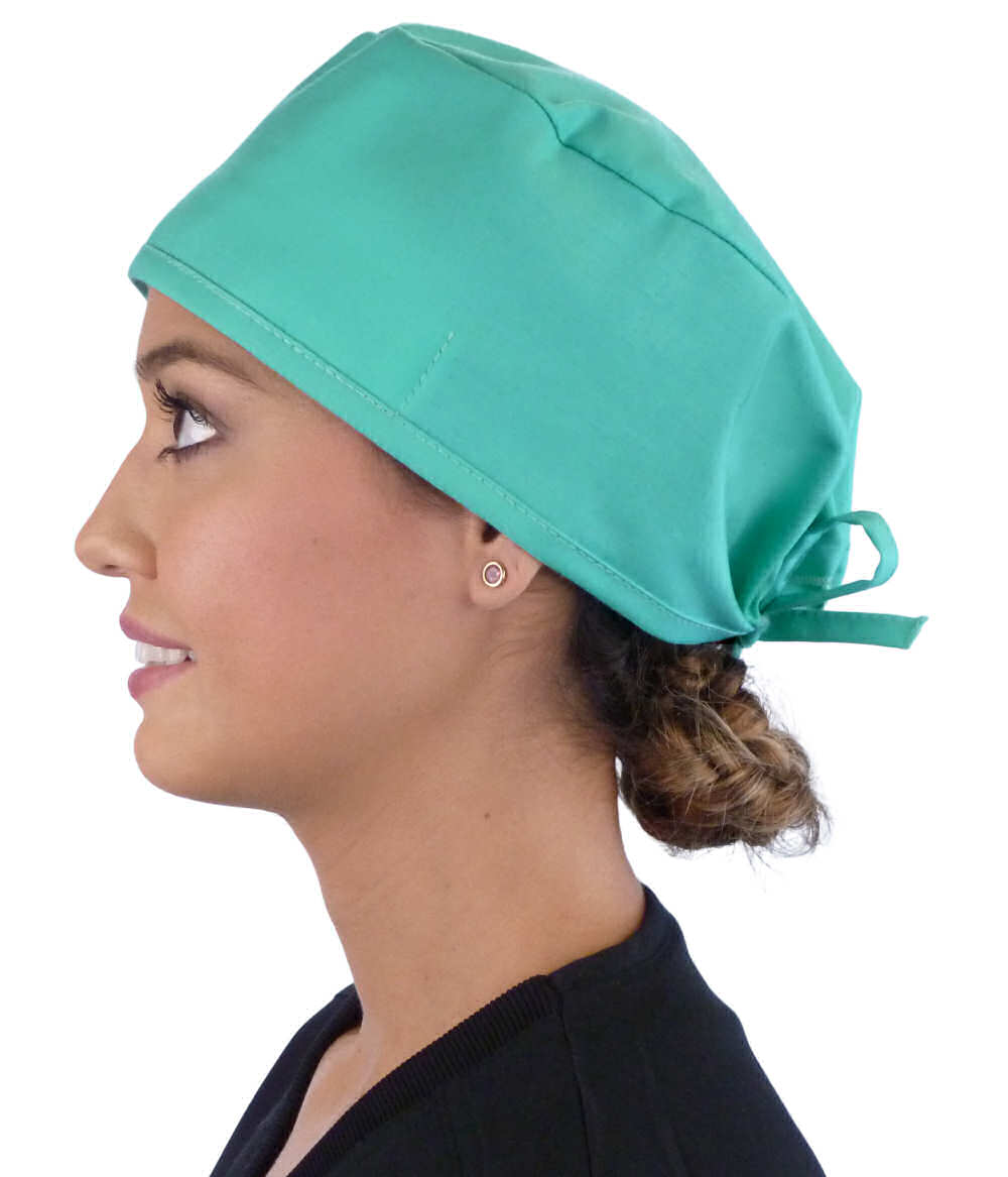 Side facing image of a woman in scrubs wearing a Classic Surgical Scrub Cap in Scrub Green.