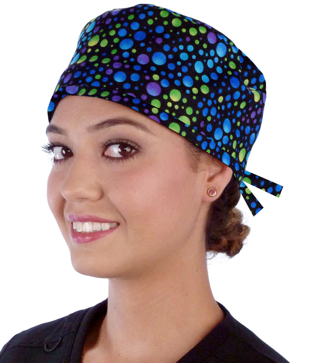 Front facing image of a woman in scrubs wearing a Classic Surgical Scrub Cap in a Blue, Green and Purple Dots pattern.