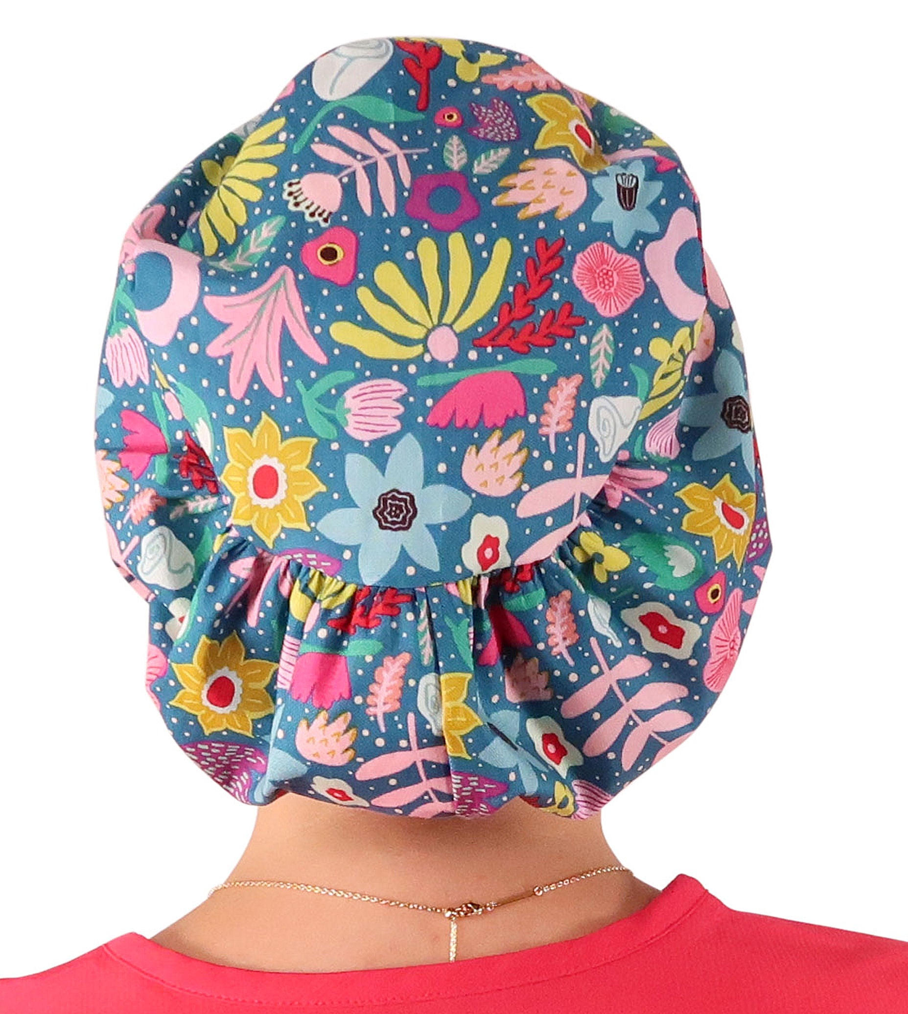 Back facing image of a woman in scrubs wearing a Floating Flowers Euro Style Riley Comfort Scrub Cap.
