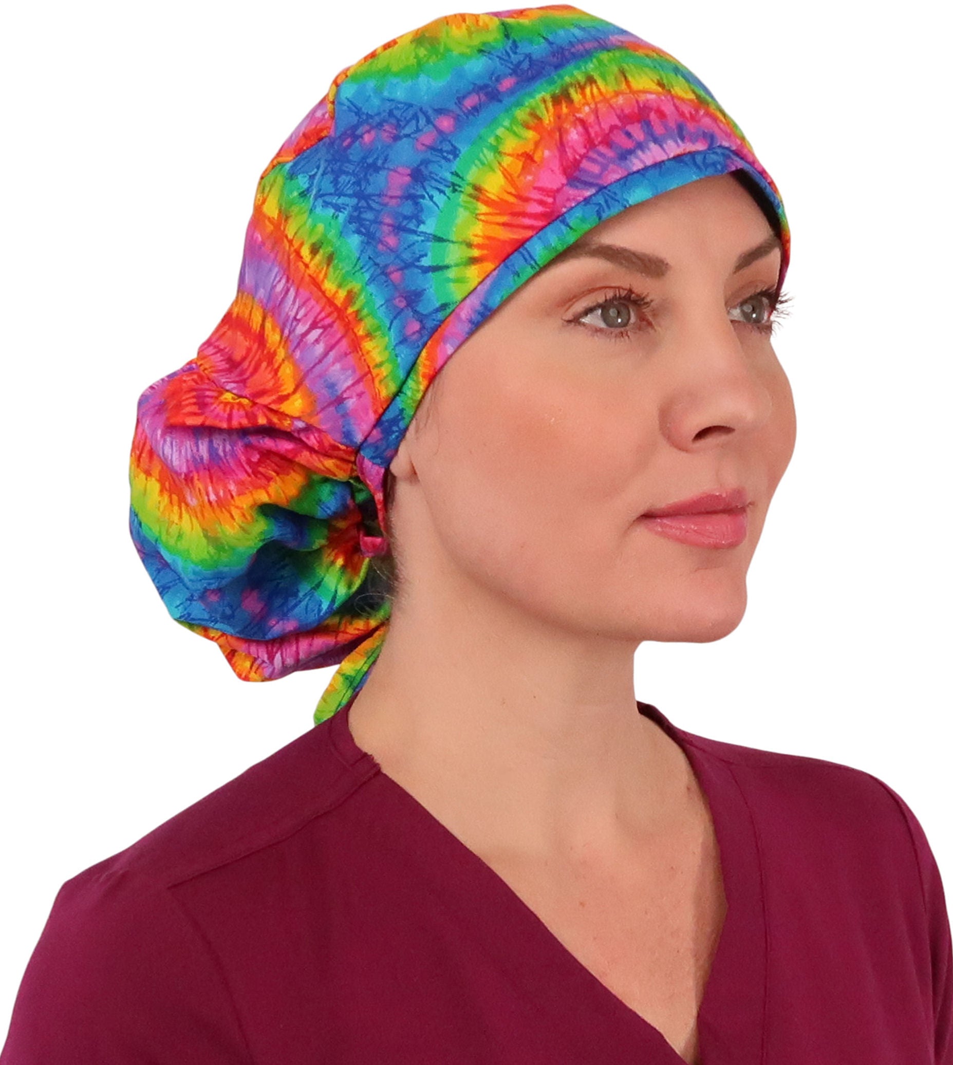 Front facing image untied of a woman in scrubs wearing a Big Hair Ponytail Scrub Cap with a Tie Dye pattern.