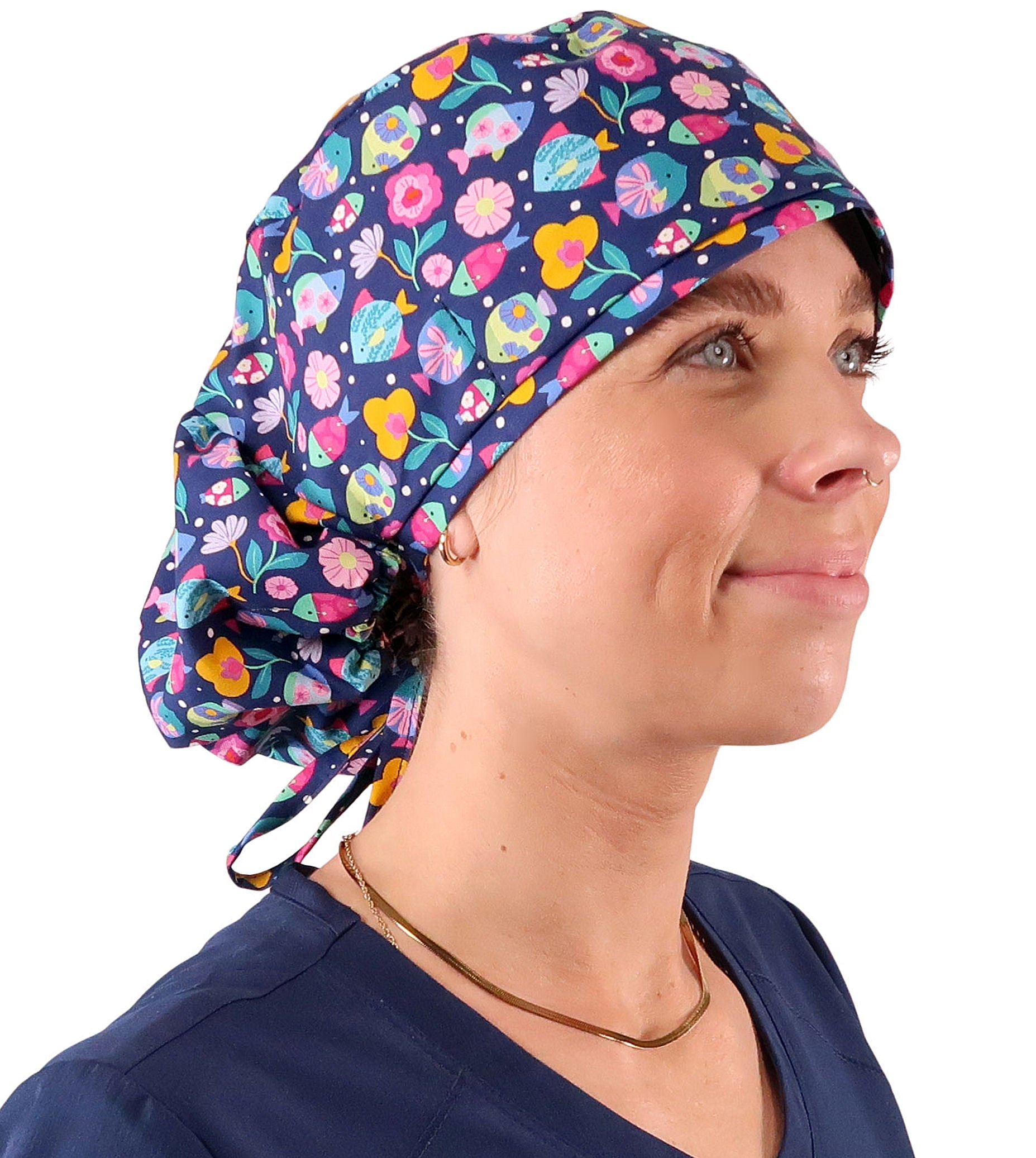 Side facing untied image of a woman in scrubs wearing a Big Hair Ponytail Scrub Cap with a Fabulous Fishies pattern.