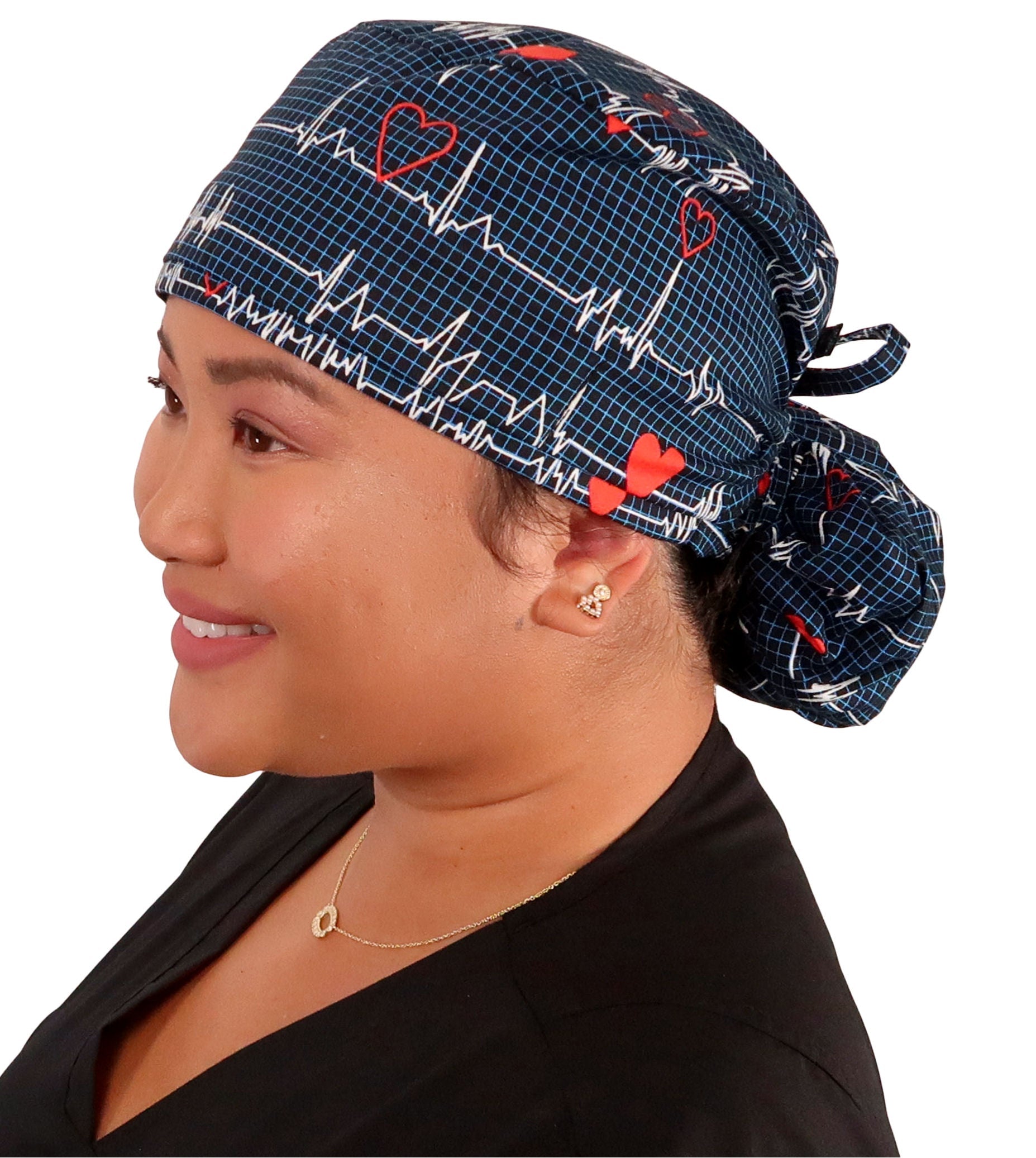 Side facing image tied of a woman in scrubs wearing a Big Hair Ponytail Scrub Cap with a Heartbeats on Navy pattern.