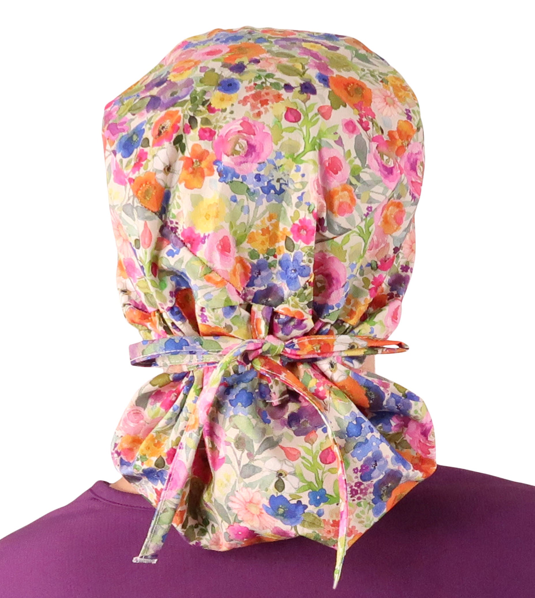 Back facing tied image of a woman in scrubs wearing a Big Hair Ponytail Scrub Cap with a Wondrous Wildflowers pattern.