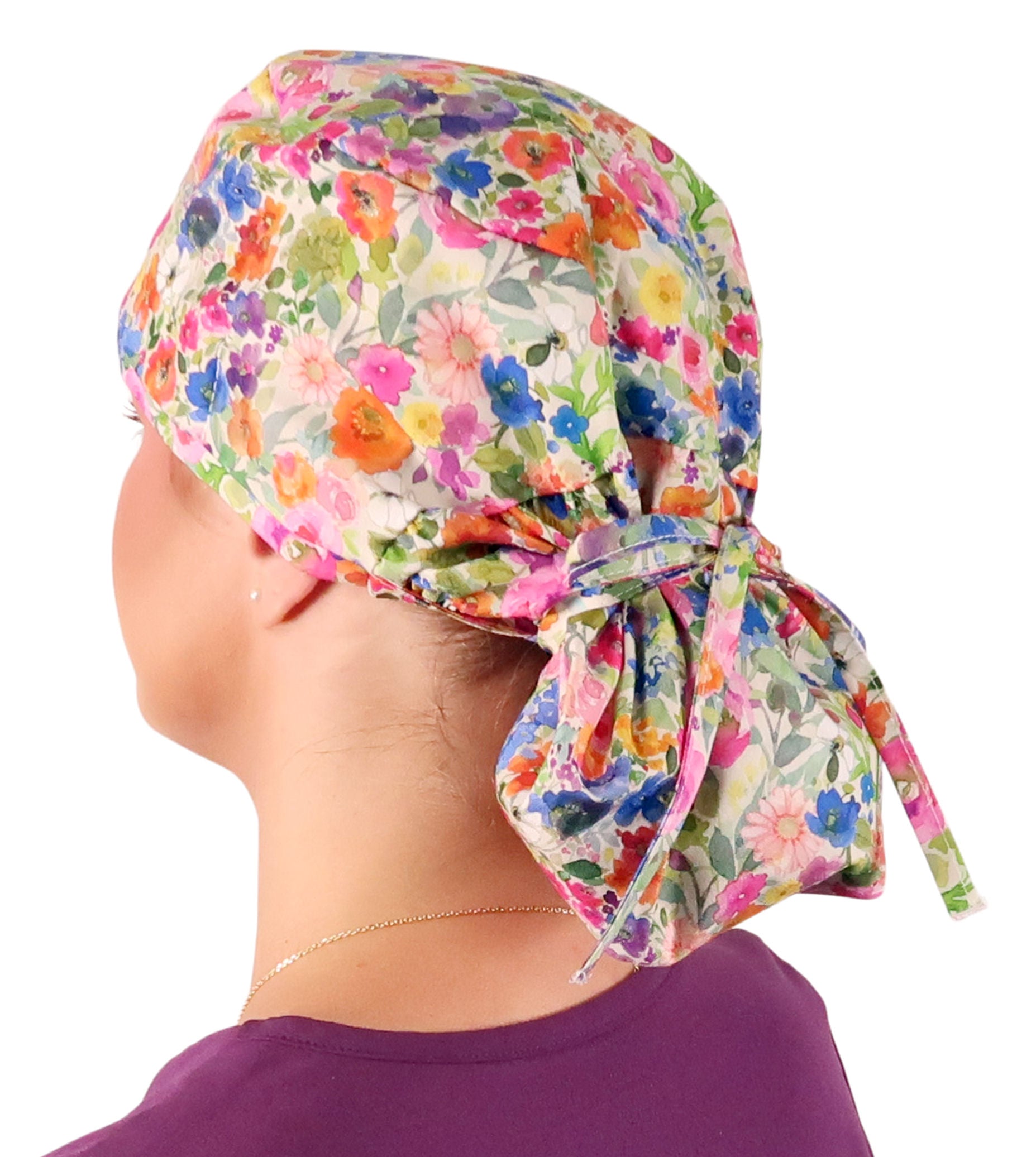 Side facing tied image of a woman in scrubs wearing a Big Hair Ponytail Scrub Cap with a Wondrous Wildflowers pattern.