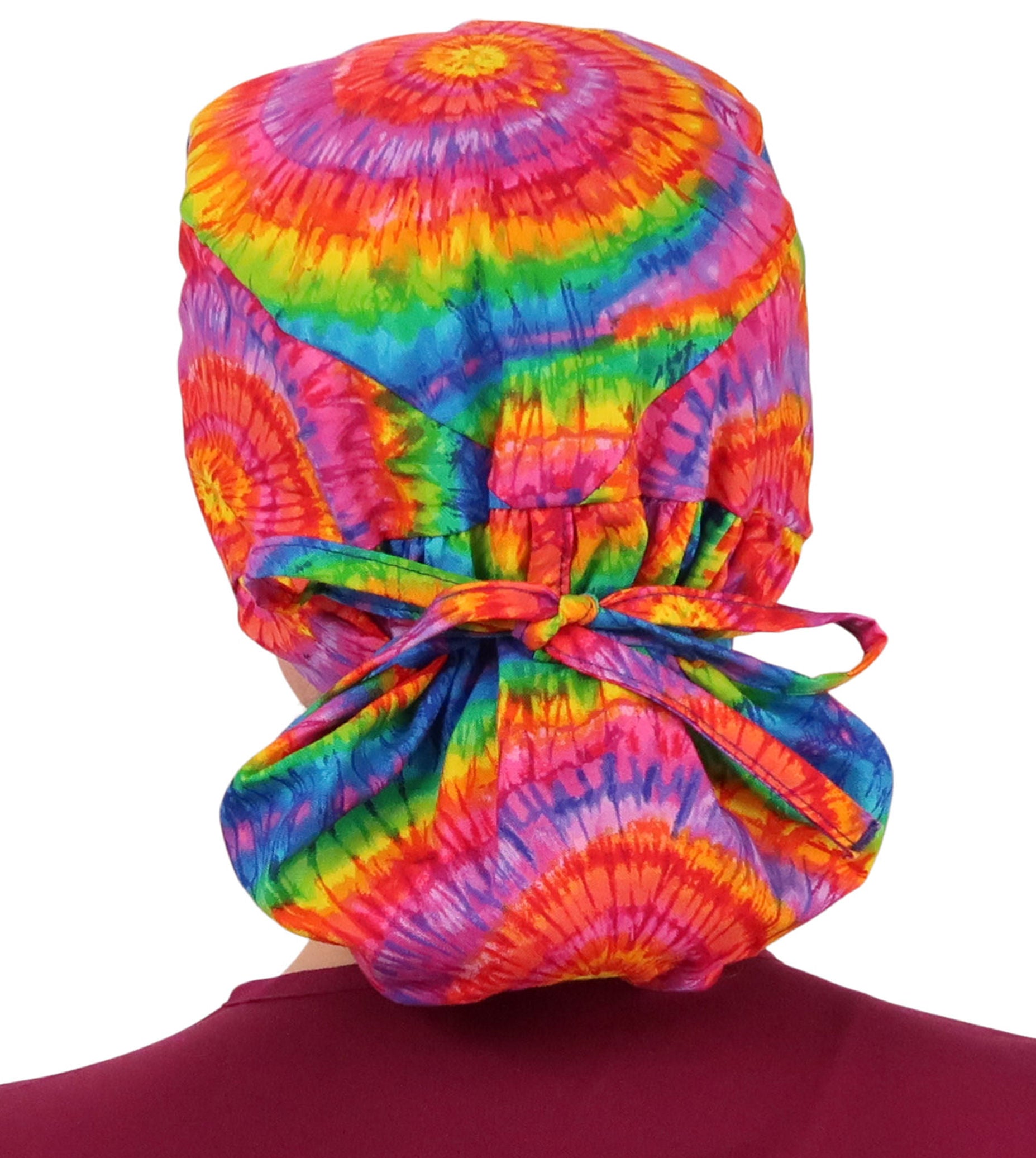 Back facing image tied of a woman in scrubs wearing a Big Hair Ponytail Scrub Cap with a Tie Dye pattern.
