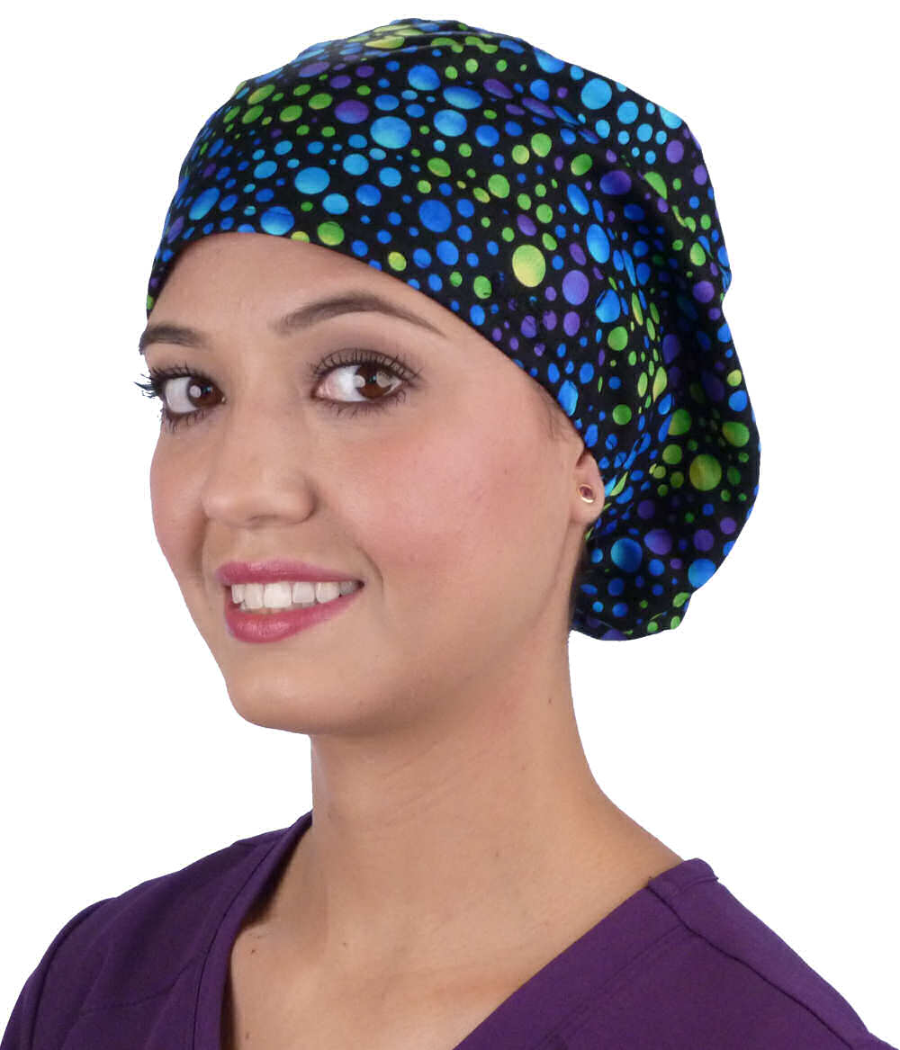Front facing image of a woman in scrubs wearing a Blue, Green and Purple Dots Euro Style Riley Comfort Scrub Cap.