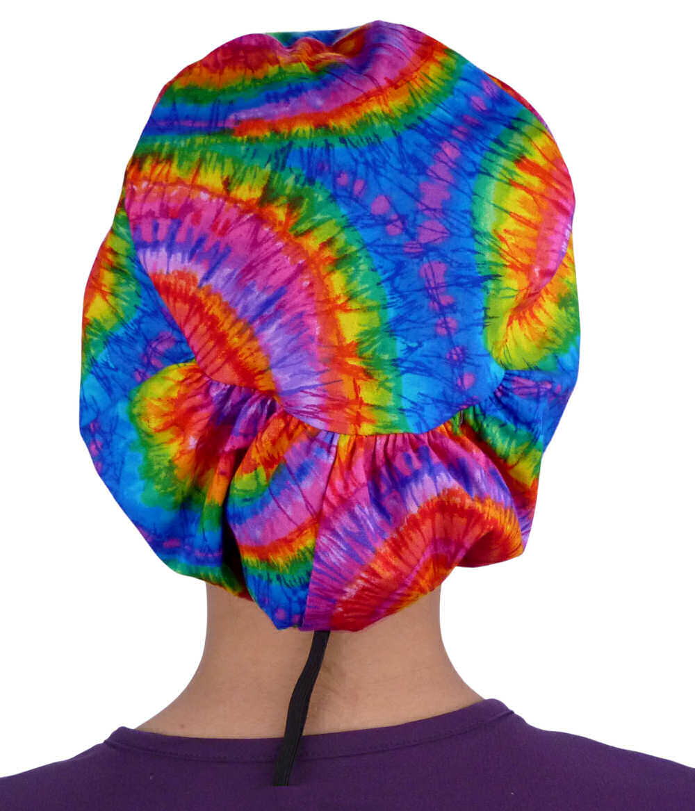 Back facing image of a woman in scrubs wearing a Tie Dye Euro Style Riley Comfort Scrub Cap.
