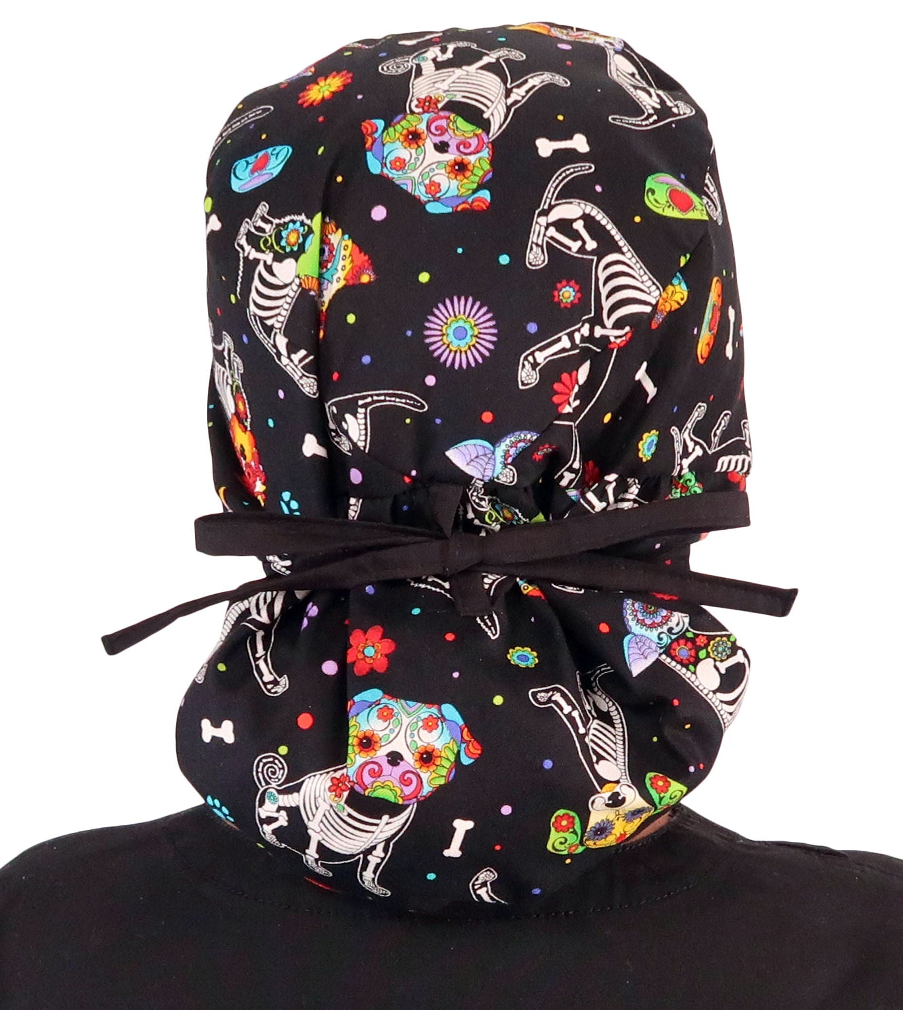 Back facing tied image of a woman in scrubs wearing a Big Hair Ponytail Scrub Cap with a X-Ray Dogs pattern, and black ties to hold the scrub cap in place.