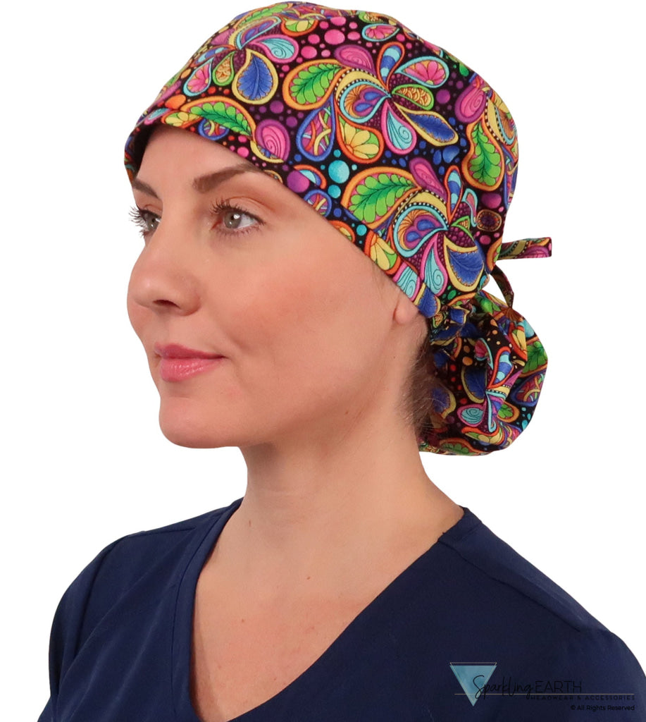 Front facing tied image of a woman in scrubs wearing a Big Hair Ponytail Scrub Cap with a Bright Flower Paisley pattern