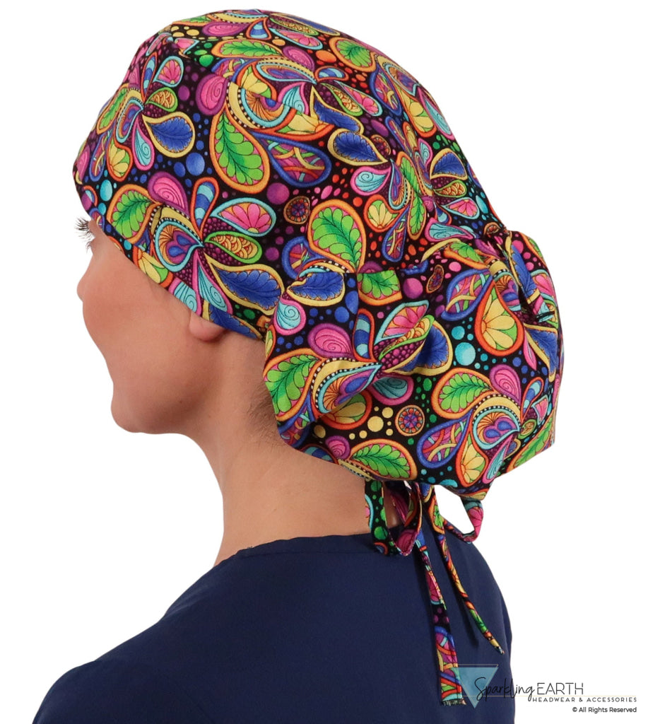 Side facing untied image of a woman in scrubs wearing a Big Hair Ponytail Scrub Cap with a Bright Flower Paisley pattern