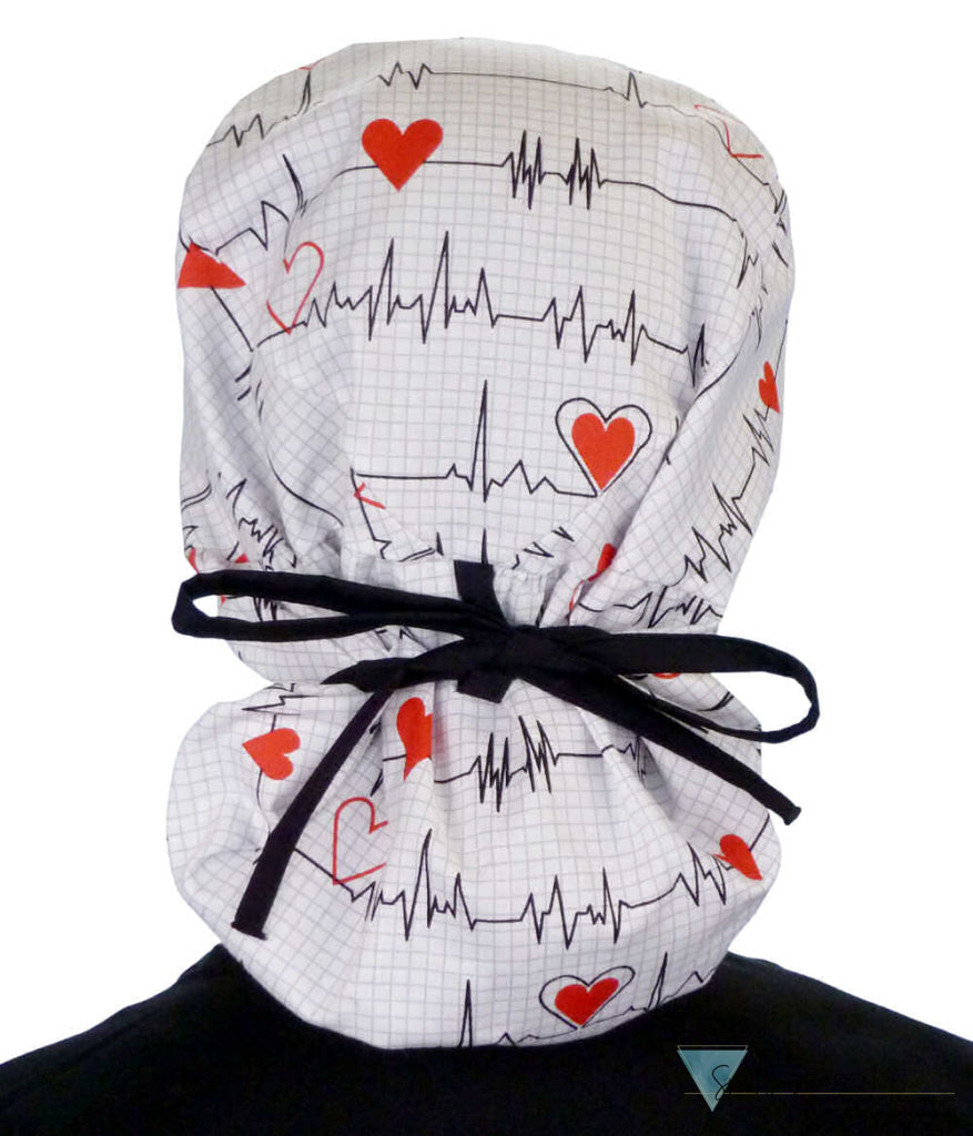 Back facing tied image of a woman in scrubs wearing a Big Hair Ponytail Scrub Cap with a Heartbeats on White pattern, and black ties to hold the scrub cap in place.