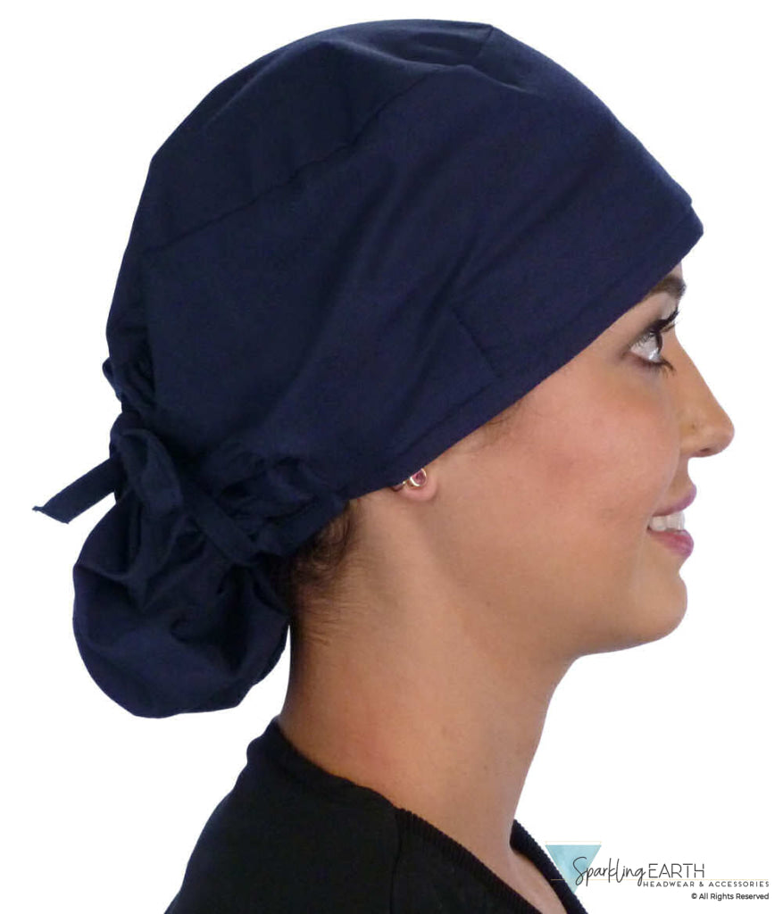 Side facing tied image of a woman in scrubs wearing a Navy Big Hair Ponytail Scrub Cap and navy ties to hold the scrub cap in place.