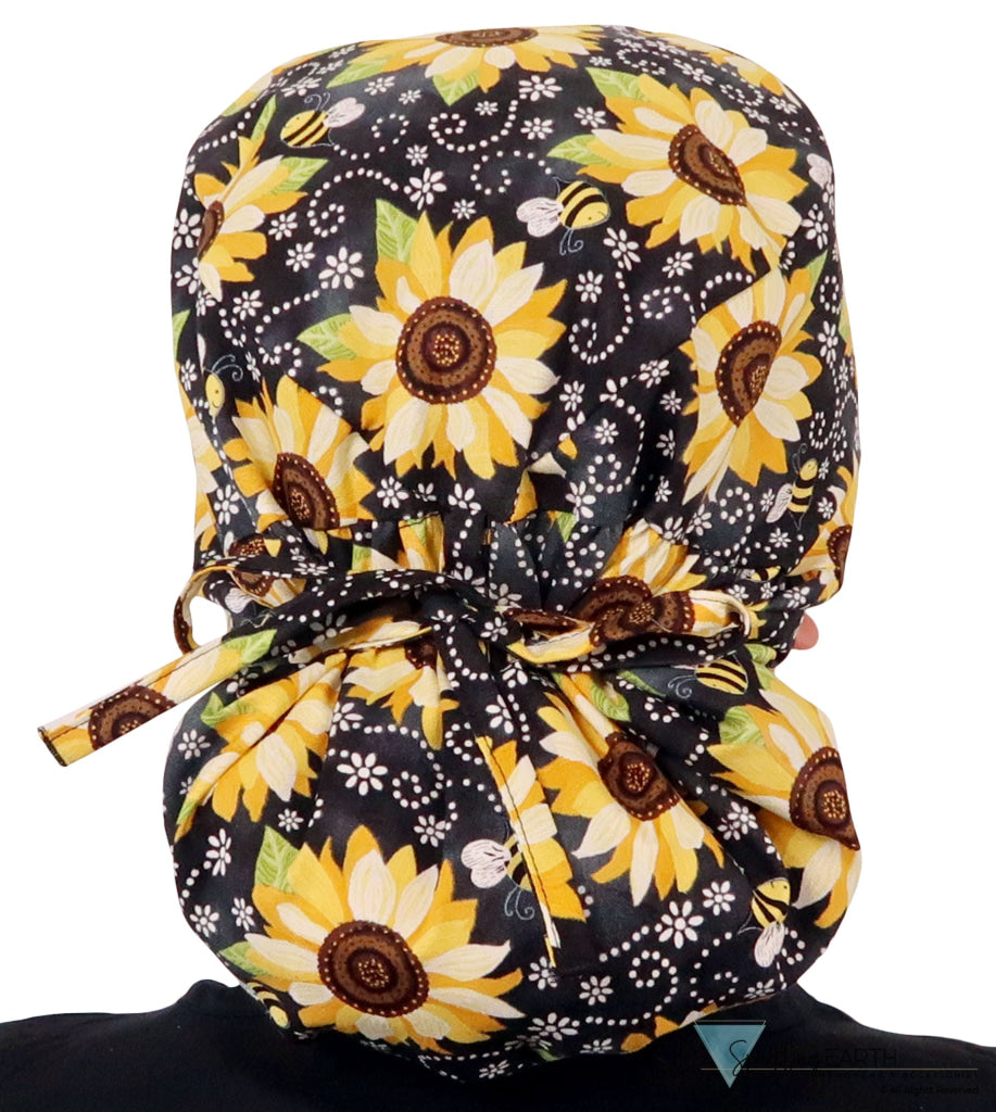 Back facing tied image of a woman in scrubs wearing a Big Hair Ponytail Scrub Cap with a Sunflowers on Black pattern.