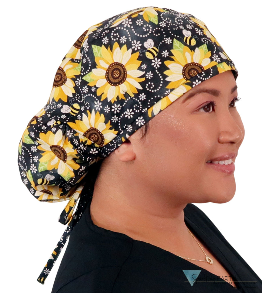 Side facing untied image of a woman in scrubs wearing a Big Hair Ponytail Scrub Cap with a Sunflowers on Black pattern.