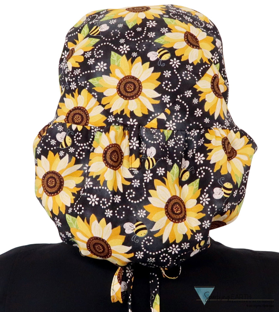 Back facing untied image of a woman in scrubs wearing a Big Hair Ponytail Scrub Cap with a Sunflowers on Black pattern.