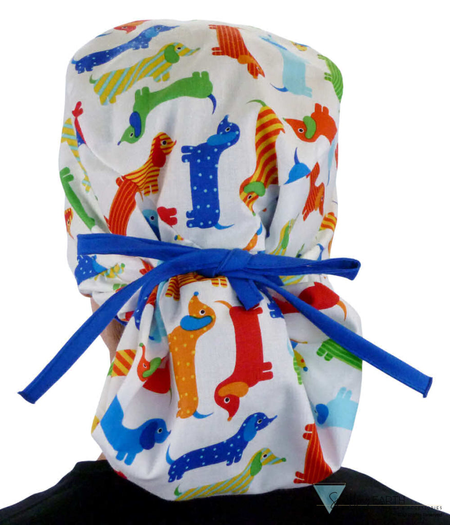 Back facing tied image of a woman in scrubs wearing a Big Hair Ponytail Scrub Cap with a Tossed Wiener Dogs pattern, and royal ties to hold the scrub cap in place.