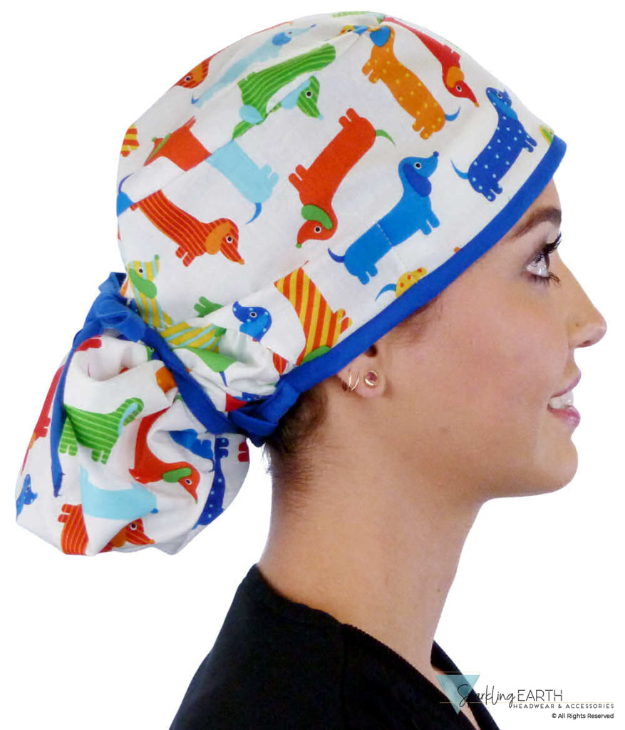Side facing tied image of a woman in scrubs wearing a Big Hair Ponytail Scrub Cap with a Tossed Wiener Dogs pattern, and royal ties to hold the scrub cap in place.