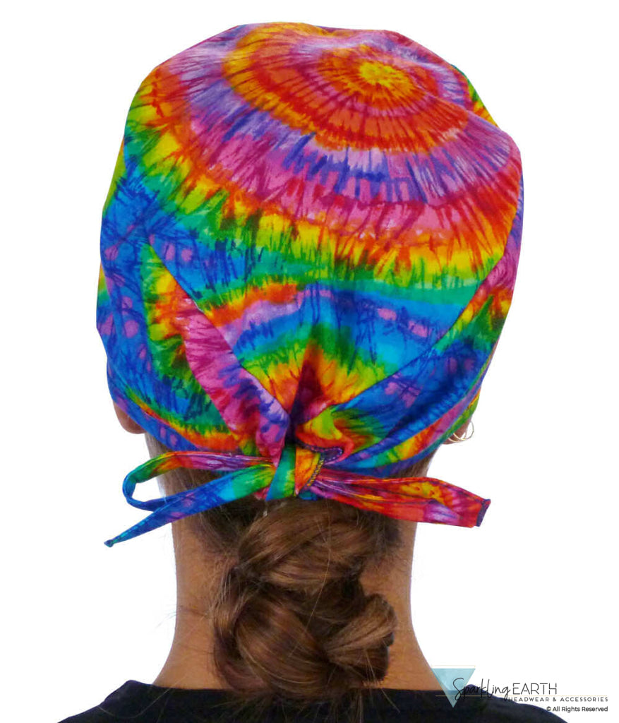 Back facing image of a woman in scrubs wearing a Classic Surgical Scrub Cap in a Tie Dye pattern.