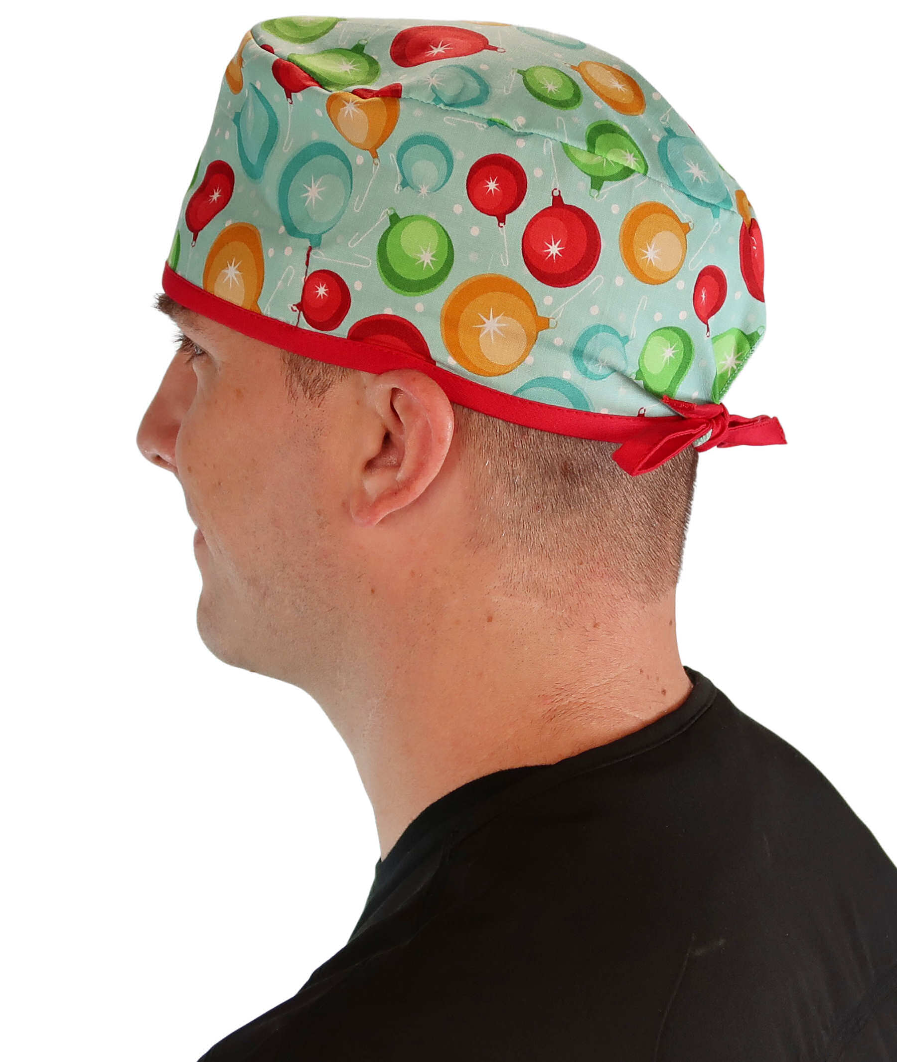 Side facing image of a man in scrubs wearing a Classic Surgical Scrub Cap with a Christmas Ornaments with Red Ties pattern.