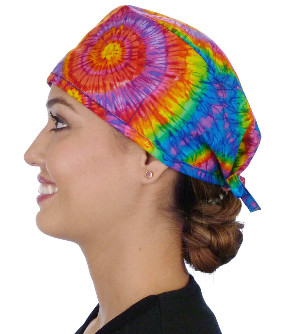 Side facing image of a woman in scrubs wearing a Classic Surgical Scrub Cap in a Tie Dye pattern.
